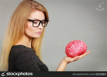 Intellectual expressions, being focused concept. Closeup of attractive woman thinking face expression holding brain. Woman thinking and holding fake brain