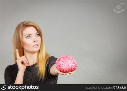 Intellectual expressions, being focused concept. Closeup of attractive woman thinking face expression holding brain. Woman thinking and holding fake brain