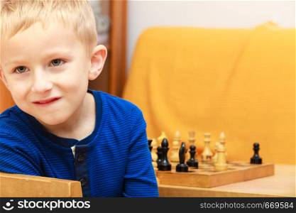 Intelligent, smart ass kids, games good for brain intelligence concept. Young kid boy playing chess and having fun.. Young kid boy playing chess having fun