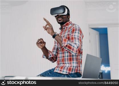 Interactive virtual reality goggles. African student in vr glasses at home office. Freelancer is working on design project. Digital technology for business and e-learning. Virtual distant study.. Interactive virtual reality goggles. African student in vr glasses at home office.