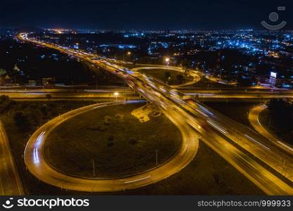 interchange freeway high way motorway and ring road transportation logistics connect in the city with lighting the city background at night in Thailand aerial view