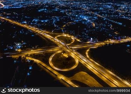 interchange freeway high way motorway and ring road transportation logistics connect in the city with lighting the city background at night in Thailand aerial view