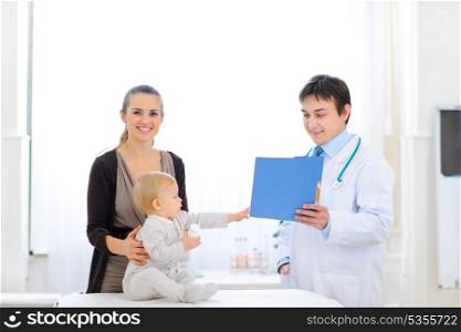 Interested baby reaches out to patients card in hand of pediatrician &#xA;