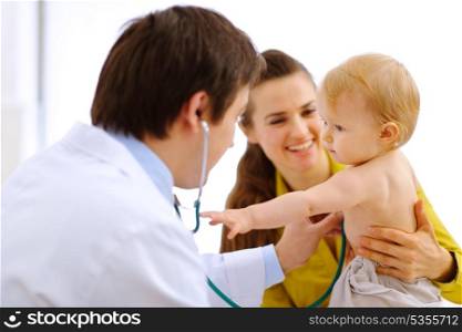 Interested baby stretching for stethoscope while being on examination&#xA;