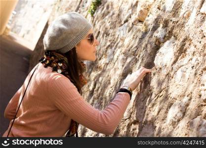 Interested Woman Looking Into A Hole In A Stone Wall