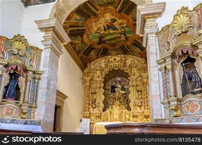 Interior and altar of a brazilian historic ancient church from the 18th century in baroque architecture with details of the walls in gold leaf in the city of Tiradentes, a UNESCO World Heritage Site, Minas Gerais State, Brazil. Golden decorated altar of a brazilian historic church from the 18th century in baroque architecture 