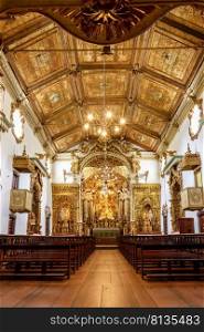 Interior and altar of a brazilian historic ancient church from the 18th century in baroque architecture with details of the walls in gold leaf in the city of Tiradentes, a UNESCO World Heritage Site, Minas Gerais State, Brazil. Interior, ceiling ornaments and altar of a brazilian historic church from the 18th century in baroque architecture