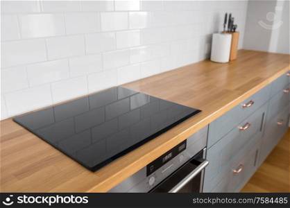 interior and cooking concept - modern kitchen counter with built in oven and electric hob at home. modern home kitchen interior with oven and hob