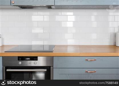 interior and cooking concept - modern kitchen counter with built in oven and electric hob at home. modern home kitchen interior with oven and hob