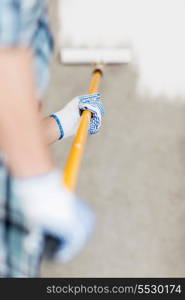 interior design and home renovation concept - man colouring the wall with roller