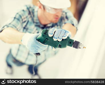 interior design and home renovation concept - man in helmet with electric drill making hole in wall