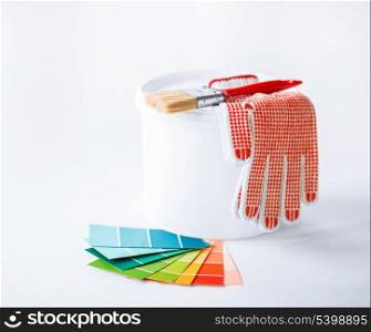 interior design and home renovation concept - paintbrush, paint pot, gloves and pantone samplers