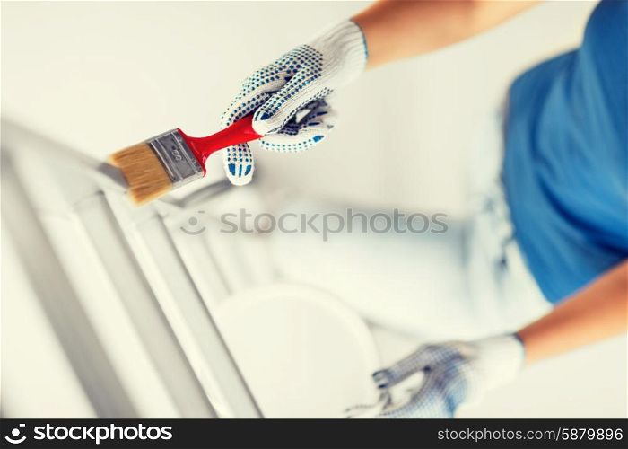 interior design and home renovation concept - woman with paintbrush and paint pot