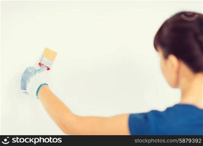 interior design and home renovation concept - woman with paintbrush colouring the wall. woman with paintbrush colouring the wall