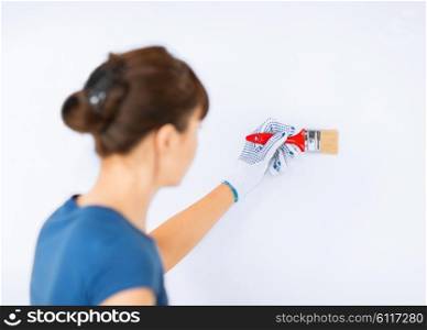 interior design and home renovation concept - woman with paintbrush colouring the wall. woman with paintbrush colouring the wall