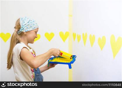 Interior Design. little Girl paints a wall in yellow