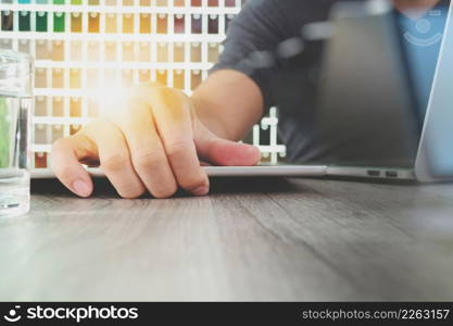 interior designer hand working with digital tablet and laptop computer and sample material on wooden desk as concept