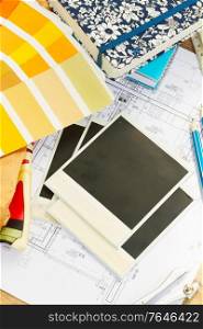 Interior designer&rsquo;s working desktop, an architectural plan of the house, color palette and fabric samples in yellow shades, copy space on instant empty photos. designer&rsquo;s working table