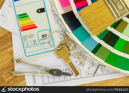 Interior designer&rsquo;s working desktop with energy rating chart, architectural plan of the house, color palette and brushes. designer&rsquo;s working table