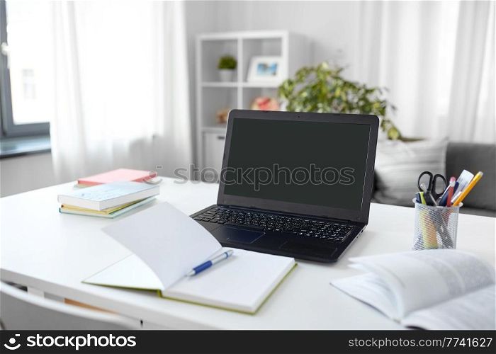 interior, education and business concept - open laptop computer, notebook and book on table at home office. laptop, notebook and book on table at home office