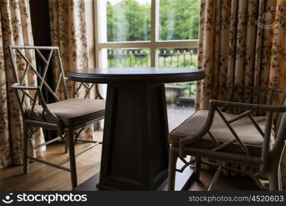interior, furniture, home and objects concept - close up of vintage chairs and table at country house