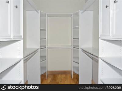 Interior of a closet with new shelves, racks and hangers for clothes, shoes and other personal items.
