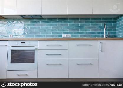 Interior of a small white kitchen with a brown top and blue tiles. Interior of a small white kitchen
