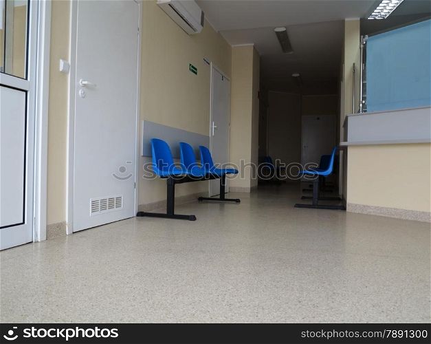 Interior of a waiting room blue stools, empty chairs.