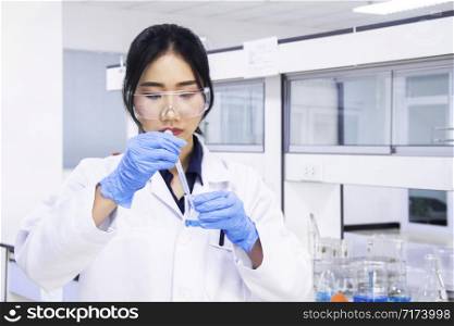 Interior of clean modern white medical or chemistry laboratory background. Laboratory scientist working at a lab with test tubes. Laboratory concept with Asian woman chemist.