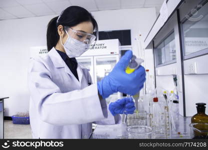 Interior of clean modern white medical or chemistry laboratory background. Scientist working at a lab with micro pipette and test tubes. Laboratory concept with Asian woman chemist. Selective focus.