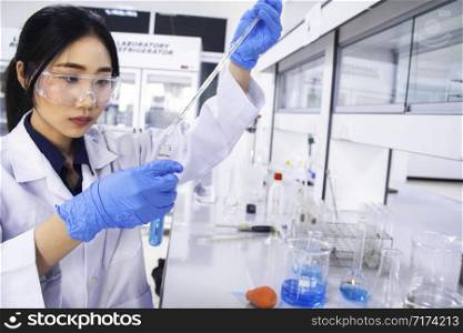 Interior of clean modern white medical or chemistry laboratory background. Laboratory scientist working at a lab with micropipette/pipette and test tubes. Laboratory concept with Asian woman chemist.