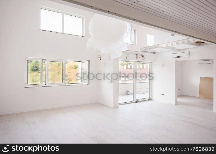 Interior of empty stylish modern open space two level apartment with white walls and large round chandelier in the middle ready to move in