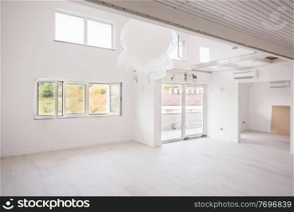 Interior of empty stylish modern open space two level apartment with white walls and large round chandelier in the middle ready to move in
