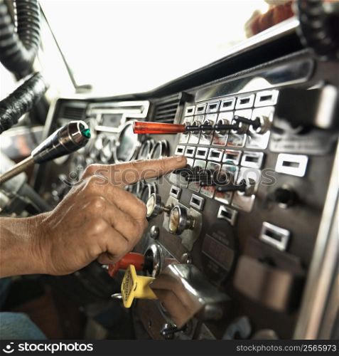 Interior of mid-adult Caucasian male hand pressing switch on dashboard of a tractor trailer.