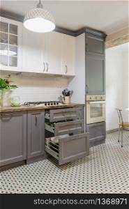 interior of modern luxury grey and white wooden kitchen, some drawers are open. modern grey and white wooden kitchen interior