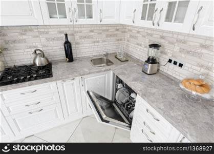 interior of modern white wooden kitchen in luxury home, dishwasher door is open. modern white wooden kitchen interior