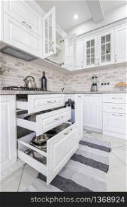 interior of modern white wooden kitchen in luxury home, some drawers are open. modern white wooden kitchen interior