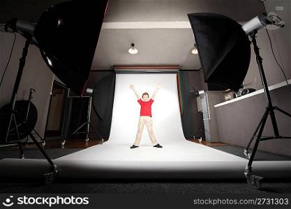 interior of professional photo studio boy in red shirt standing on white background