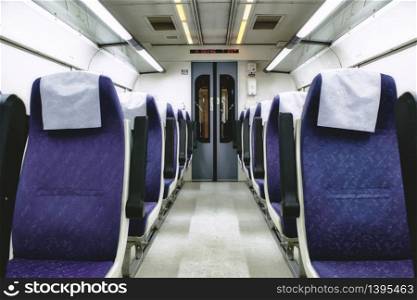 Interior of train carriage between rows of empty chairs
