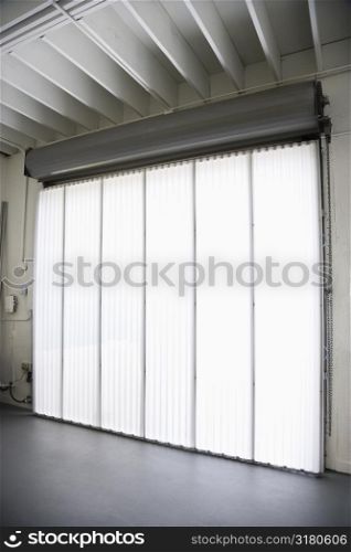 Interior of warehouse building with large window and vertical blinds.