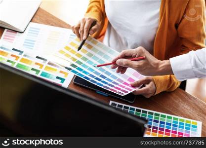 Interior or Graphic designer meeting discussing about color chart in studio.