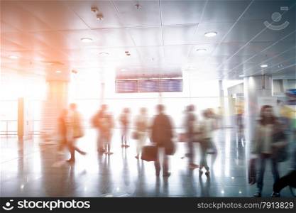 Interior photo of blurred passengers looking at airport schedule at sunny day