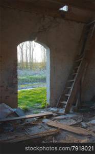 interiror from abandoned house with old wooden ladder and view to old entrance at the formal garden