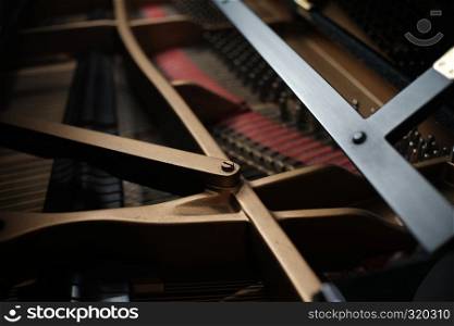 internal parts of an upright piano strings and a tuning key on the pins