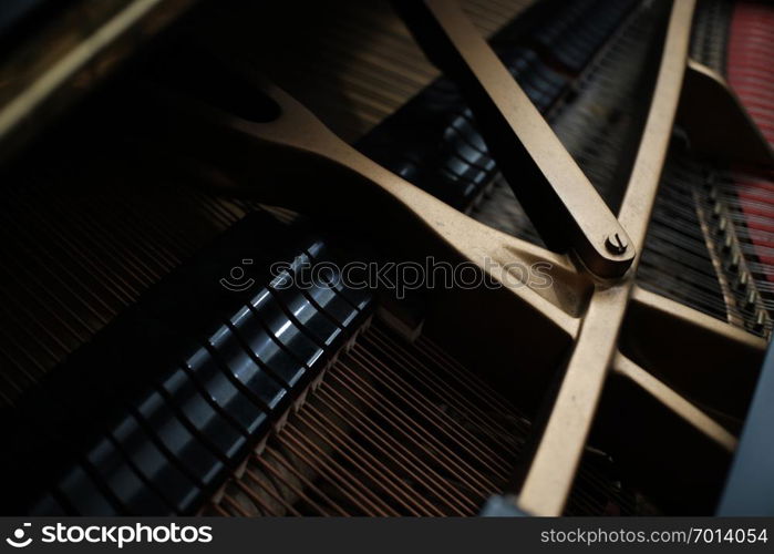 internal parts of an upright piano strings and a tuning key on the pins