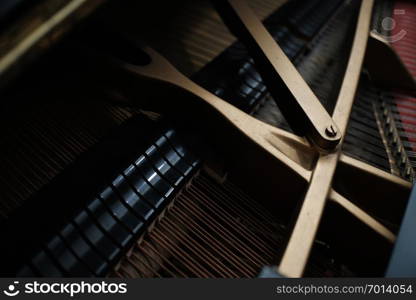 internal parts of an upright piano strings and a tuning key on the pins