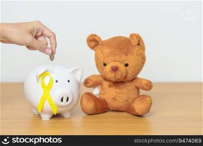 International Childhood Cancer Awareness month, Children toy with golden yellow color Ribbon with Piggy Bank for Donation, Charity, Campaign, Money Saving, Fund and World cancer day concept