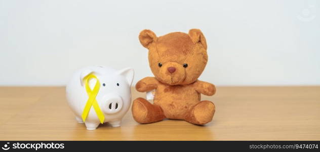 International Childhood Cancer Awareness month, Children toy with golden yellow color Ribbon with Piggy Bank for Donation, Charity, C&aign, Money Saving, Fund and World cancer day concept