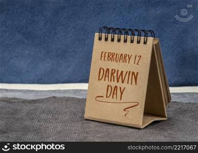 International Darwin Day, February 12 - handwriting in a desktop calendar against abstract paper landscape, reminder of Charles Darwin birthday