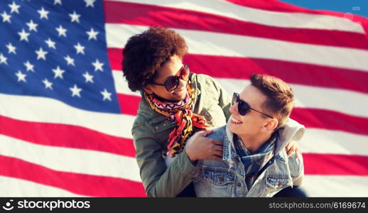 international friendship, freedom and people concept - happy teenage couple in shades having fun over american flag background